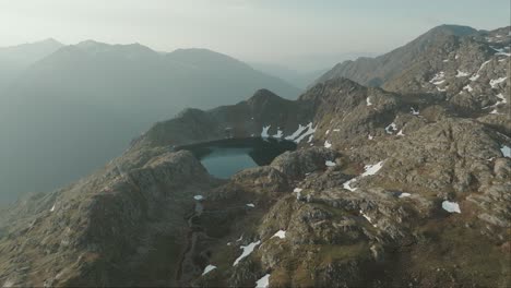 Scenic-aerial-drone-view-of-a-vivid-blue-mountain-lake-nestled-amongst-sharp-peaks-deep-in-the-Austrian-Alps