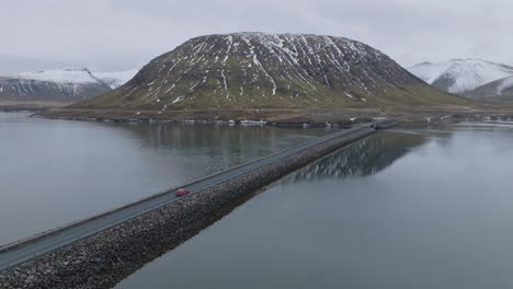 Drone-Shot-of-Car-Moving-on-Road-Between-Two-Sides-Of-Glacial-Lake-in-Landscape-of-Iceland