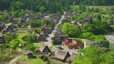 Hand-held-establishing-of-the-thatched-roof-houses-of-Shirakawago-Japan,-panoramic-viewpoint-greenish-vegetation