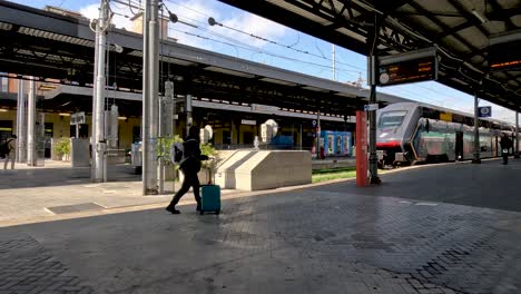 Passenger-Pushing-Wheeled-Luggage-Across-Platform-To-Train-At-Bologna-Centrale