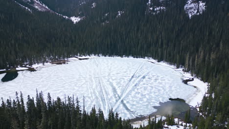 Aerial-tilt-down-flying-towards-frozen-Lower-Joffre-Lake,-Canada