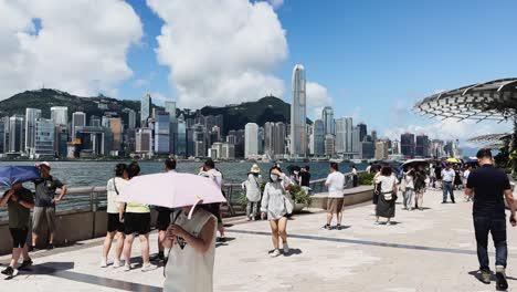 Día-Soleado-En-El-Paseo-Marítimo-De-Tsim-Sha-Tsui-Con-Turistas-Disfrutando-Del-Horizonte-De-Hong-Kong