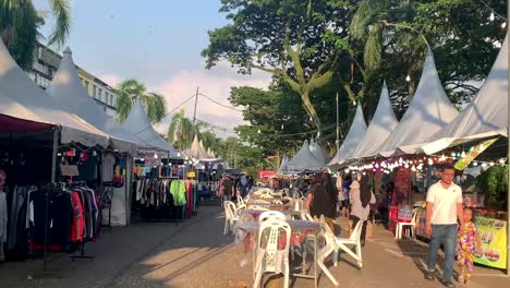 Ein-Nachtmarkt-Bei-Sonnenuntergang,-Auf-Dem-Lebensmittel-Und-Kleidung-Entlang-Der-Straße-Ausgestellt-Werden-Und-Bei-Dem-Menschen-Ein--Und-Ausgehen