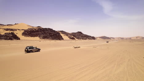 Vehicles-Driving-Along-The-Sand-Dunes-Of-Djanet-Desert-In-Algeria---drone-shot