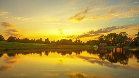 Yellow-and-blue-time-lapse-on-the-edge-of-a-pond-with-a-cottage-in-the-distance