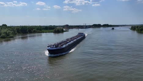 Grünes-Tankschiff,-Das-Sich-Auf-Einem-Fluss-Mit-Bäumen-Im-Hintergrund-Bewegt