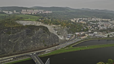 Usti-nad-Labem-Czechia-Aerial-v3-flyover-Elbe-river-across-Mariansky-Most-bridge-towards-Lom-Mariánská-Skála-quarry-site,-panning-reveals-hillside-cityscape---Shot-with-Mavic-3-Cine---November-2022