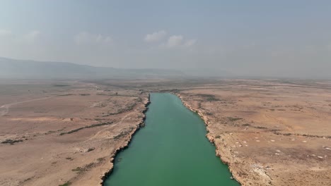 Fliegen-über-Einem-Bläulich-grünen-Fluss-Mit-Bewegungslosem-Wasser-Im-Norden-Von-Sokotra,-Jemen