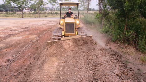 Young-worker-driving-a-grader-to-level-the-ground-in-the-construction-of-a-residential-house