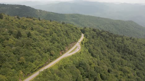 Car-drives-up-lush-forest-highway-to-Smoky-mountain-summit-ridge
