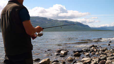 Fisherman-use-spinning-in-Norway-lake,-close-up-back-view