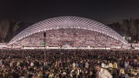 Timelapse-shot-of-huge-crowd-of-locals-gathering-just-before-the-starting-of-Latvian-Song-and-Dance-Festival-in-an-outdoor-stadium-in-Riga,-Latvia-during-evening-time