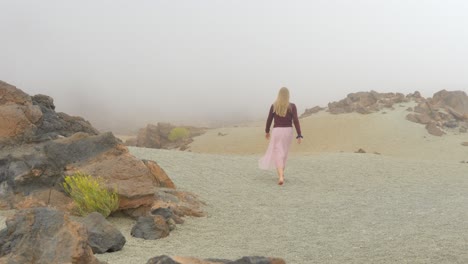 Blonde-woman-walking-in-foggy-landscape-in-desertic-Teide-national-park