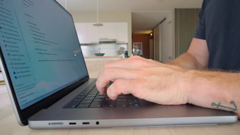 Man-Typing-Quickly-on-His-Laptop-on-the-Countertop-of-the-Kitchen
