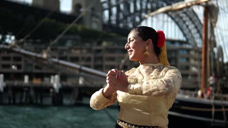 Mujer-Del-Sur-De-Asia-Disfrazada-Interpretando-Danza-India-Clásica-Junto-Al-Puente-Del-Puerto-De-Sydney-En-Sydney,-Australia