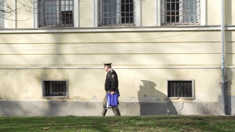 Following-shot-of-a-security-guard-walking-past-a-government-building-towards-his-job-during-morning-time