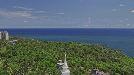 Unawatuna-Sri-Lanka-Aerial-v12-reverse-flyover-hillside,-reveals-Japanese-Peace-Pagoda-on-Rumassala-hill-and-tropical-jungle-beach-and-exotic-summer-ocean-views---Shot-with-Mavic-3-Cine---April-2023