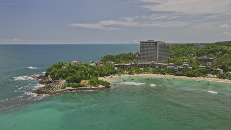 Unawatuna-Sri-Lanka-Aerial-v1-cinematic-drone-flyover-bay-capturing-rocky-shoreline,-Yaddehimulla-resort-hotels-with-exotic-beach-and-turquoise-sea-water-views---Shot-with-Mavic-3-Cine---April-2023