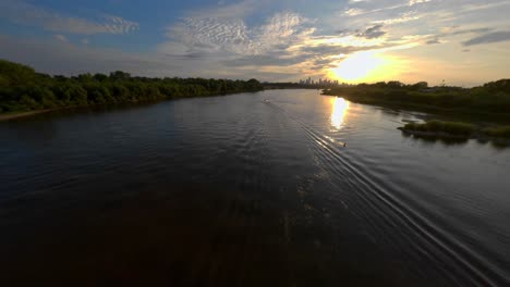 Verfolgung-Eines-Motorboots-Mit-Einer-FPV-Drohne-Auf-Der-Weichsel-Bei-Sonnenuntergang-Mit-Der-Stadt-Warschau-Im-Hintergrund