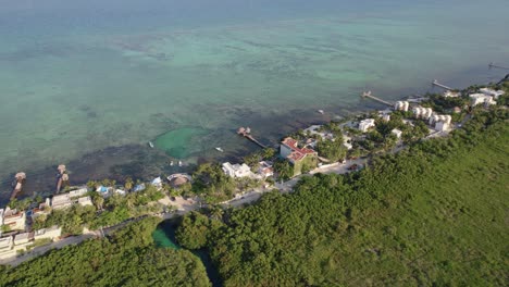Wide-aerial-view-of-tropical-villa,-resort,-and-hotels-on-the-ocean-by-a-rainforest-in-Tulum,-Mexico