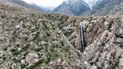 Nach-Oben-Gerichteter-Wasserfall-Mit-Schneebedeckten-Bergen-Im-Hintergrund-In-Der-Wüste-Von-Palm-Springs,-Ca