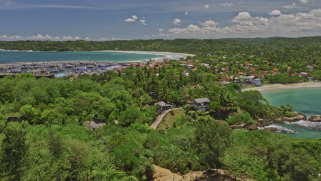 Kudawella-Sri-Lanka-Aerial-v8-cinematic-drone-flyover-rocky-shore-capturing-Hummanaya-blowhole,-fishing-village,-marina-harbor,-sandy-beach-views-on-a-sunny-day---Shot-with-Mavic-3-Cine---April-2023