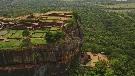 Sigiriya-Sri-Lanka-Aerial-v6-fly-around-Sigiriya-Rock-capturing-ancient-hilltop-fortress,-historical-ruins-of-Lion's-paw-and-terrace-surrounded-by-lush-forests---Shot-with-Mavic-3-Cine---April-2023