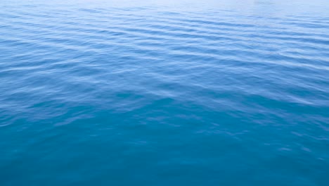 Bright-calm-blue-deep-ocean-water-ripples-and-flows-left-to-right