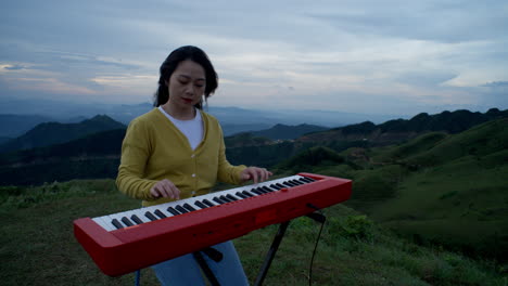 A-young-woman-sits-atop-a-hill,-her-fingers-dancing-across-the-keyboard-as-she-plays-a-beautiful-melody