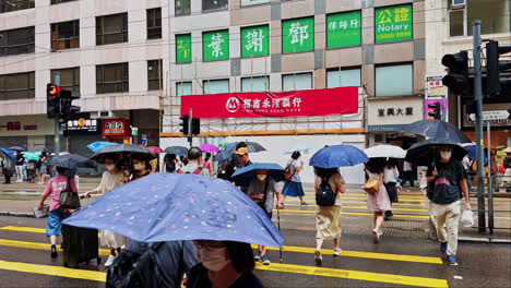 Fußgänger-Mit-Regenschirmen-überqueren-An-Einem-Regnerischen-Tag-In-Hongkong-Eine-Straße,-Zeitlupe