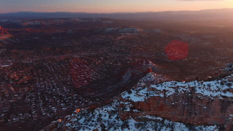 Aerial-flyover-of-snowy-Capitol-Butte,-looking-down-on-Sedona-and-vast-landscape
