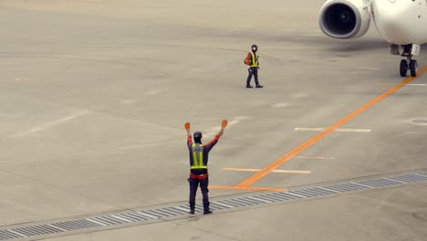 Japanese-Staff-Crew-at-Okinawa-International-Airport-making-body-signs-to-Airplane-Landing-track-approaching-Japan-Airlines