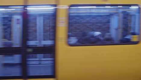 Yellow-metro-train-passing-and-stopping-in-Berlin-metro-station-of-Weberwiese