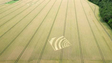 Aerial-view-circling-geometric-wave-crop-square-pattern-in-Micheldever,-Hampshire-farmland-2023