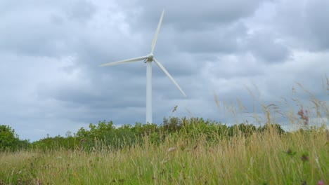 Wind-turbine-with-stormy-sky-and-low-grassy-approach