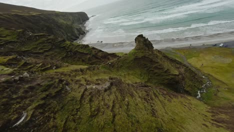 Fast-drone-shot-going-down-green-cliffs-towards-a-beautiful-beach-in-Ireland