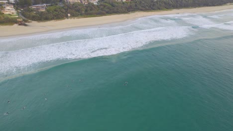 Surfistas-Flotando-En-El-Pintoresco-Océano-En-La-Playa-De-Sol-En-Queensland,-Australia---Toma-Aérea-De-Drones