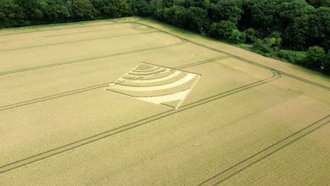Aerial-view-moving-over-mysterious-waveform-crop-square-on-Hampshire-golden-wheat-farming-countryside-2023