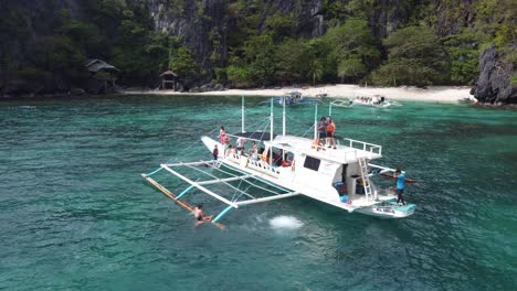 Menschen-Im-Urlaub-Genießen-Tropisches-Wasser-Und-Springen-Von-Einem-Inselhüpferboot-Am-Serenity-Beach-In-El-Nido,-Philippinen