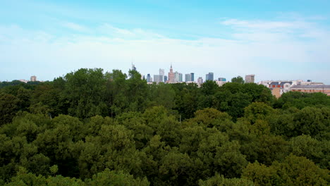 Aerial-pullback-shot-Forest-landscape-and-Skyline-of-Warsaw-in-background-with-blue-sky