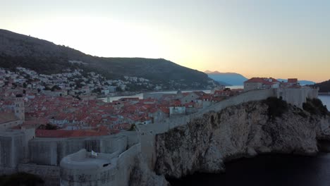 Drone-shot-revealing-old-town-surrounded-by-wall-of-Dubrovnik,-Croatia