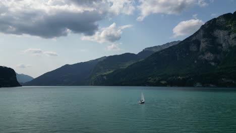 Schwenkaufnahme-Einer-Yacht,-Die-In-Den-Ruhigen-Gewässern-Des-Walensees-In-Der-Schweiz-Segelt
