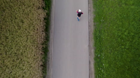 Top-down-aerial---A-runner-is-training-on-a-narrow-asphalt-road