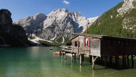 Wooden-boat-house-with-tourist-boat-on-lake-Braies-in-Dolomites-mountain,-Italy