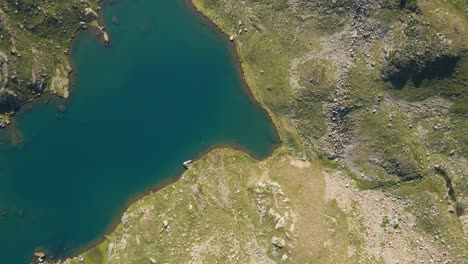 Top-down-drone-footage-of-a-turquoise-lake-in-the-Pyrenees-mountains