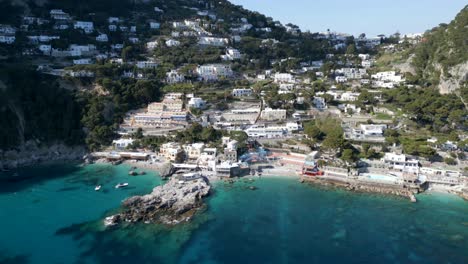 Drone-footage-of-motor-boats-in-small-bay-in-Capri,-Italy-with-rocks-and-blue-water