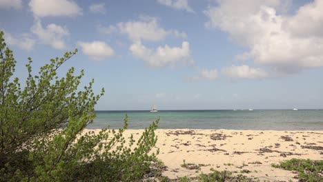Weitwinkelansicht-Des-Niedrigen-Strandes-Mit-Meer-Und-Booten-Im-Hintergrund-In-Der-Karibik
