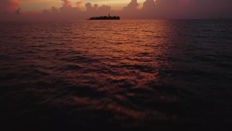 Bei-Sonnenaufgang-Durch-Den-Ozean-Fliegen,-Mit-Einer-Tropischen-Insel-Als-Hintergrund