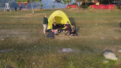 Tourists-waving-to-drones,-camping-on-the-edge-of-the-Sermo-reservoir-with-a-beautiful-view,-early-morning