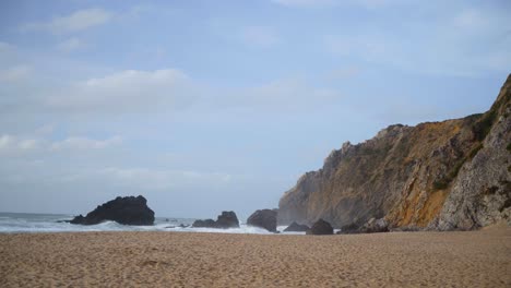 Sea-waves-crashing-at-a-hilly-beach-of-Praia-da-Adraga-in-Portugal